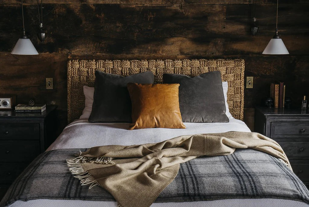 This image shows a cozy bedroom with a bed dressed in two luxurious throws and decorative pillows.