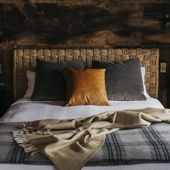 This image shows a cozy bedroom with a bed dressed in two luxurious throws and decorative pillows.